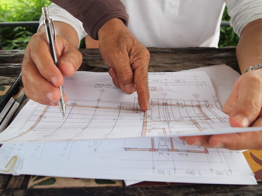 Two architects reviewing and discussing detailed blueprints at a workspace.